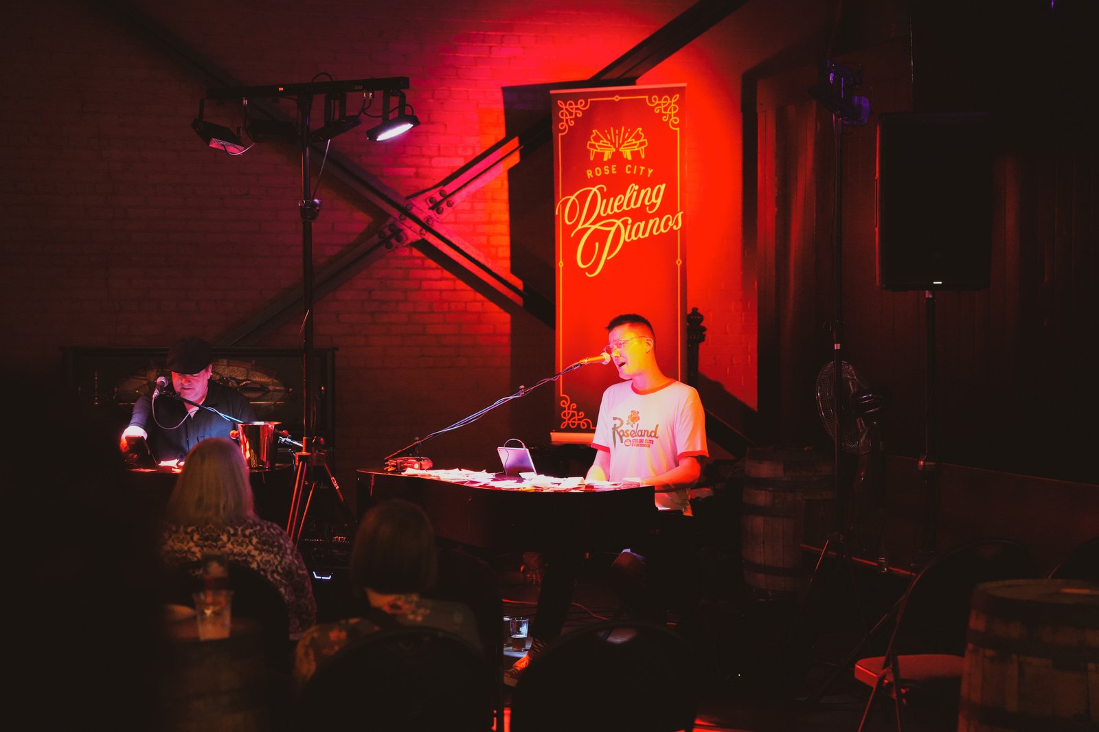 RCDP performer at piano under red stage lighting with branded banner